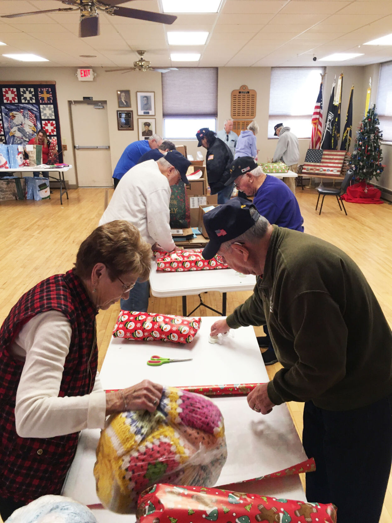Volunteers work at tables in American Legion hall on gifts for veterans home residents